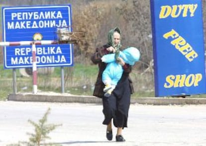 Una mujer con un bebé en brazos se dirige ayer a la frontera de Albania tras dejar su hogar en Macedonia.