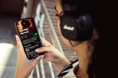 Una mujer escucha en la plataforma Spotify a la artista generada por IA 'Etta Mae Hartwell'.