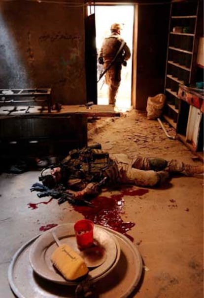 Un <i>marine</i> yace muerto en el suelo de una cocina de Faluya mientras otro revisa si aún hay insurgentes en la casa.