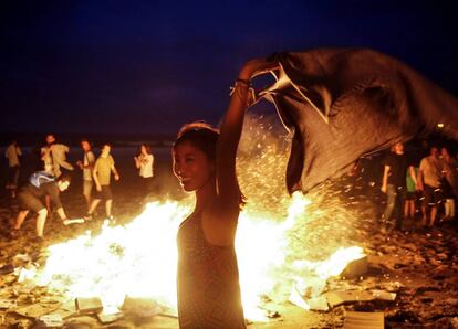 Una joven disfruta junto a una hoguera, hoy en la playa de La Zurriola de San Sebastián.