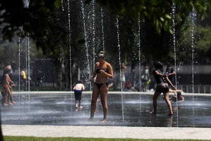 Unos jóvenes se refrescan en unos chorros de agua en Madrid Río debido a la ola de calor que sufre la península.