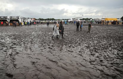 Metal fans walk on the muddy festival grounds ahead of the beginning of the Wacken Open-Air (WOA) Festival