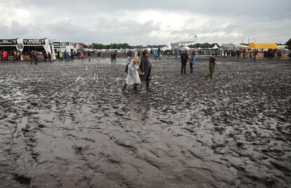 Metal fans walk on the muddy festival grounds ahead of the beginning of the Wacken Open-Air (WOA) Festival