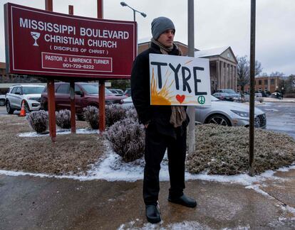 Un hombre levanta un cartel con el nombre "Tyre" escrito sobre el dibujo de un sol, un corazón y un símbolo de paz, a las afueras de la iglesia donde se ha celebrado el funeral. 