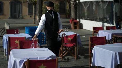 Un cambrer prepara les taules de la terrassa d'un restaurant de Barcelona, al gener.