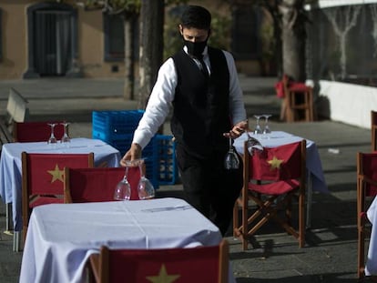 Un cambrer prepara les taules de la terrassa d'un restaurant de Barcelona, al gener.
