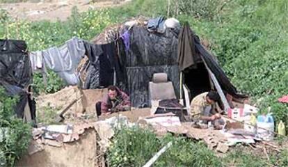 Dos inmigrantes se preparan la comida en el campamento donde viven