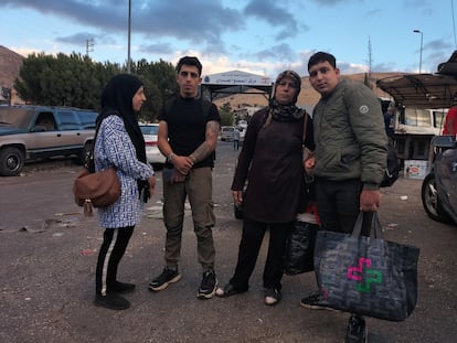 Ali Haidar Mahdi, second from left, and Nahida Al Matbuh, second from right, in front of the sign at the Masnaa border post with Syria, on the Lebanese side, on Tuesday.