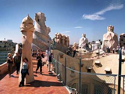 Turistas en la terraza barcelonesa de La Pedrera o Casa Milá, de Gaudí, rodeados por escultóricas chimeneas modernistas