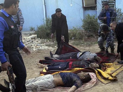 Policías iraquíes colocan sobre mantas los cuerpos de tres de los prisioneros muertos.