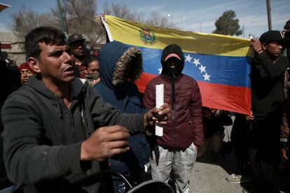 Migrantes, dos de ellos con la bandera venezolana, se reúnen alrededor del centro donde el INM tenía detenidos a los migrantes que fallecieron el martes por la madrugada.