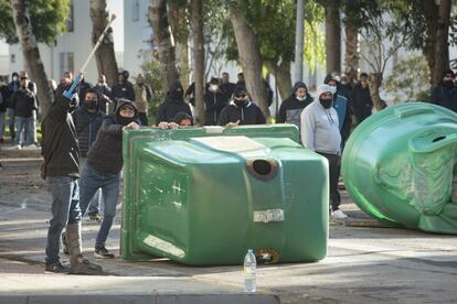 Un grupo de manifestantes forma una barricada con un contenedor de vidrio durante las protestas que han tenido lugar en Puerto Real.