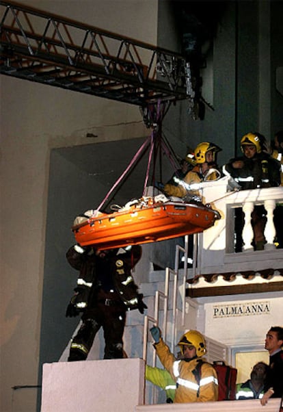 Los bomberos evacuan a un vecino cercado por el fuego (arriba).