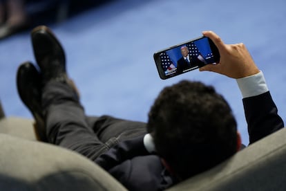 Una persona mira una transmisión en directo de la conferencia de prensa en el centro de convenciones donde tiene lugar la cumbre.