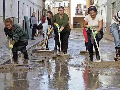 Vecinas de la barriada utrerana Coca de la Piñera limpian el lodo de las calles tras la inundación de la madrugada del miércoles. 
/ garcía cordero
Reyes Álvarez y su marido, Juan Gago, frente a su casa.