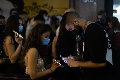 Un trabajador escanéa el código QR del móvil de una joven en la reapertura del ocio nocturno en Barcelona, este jueves. / [ALBERT GARCIA]