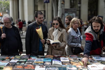 Varias personas hojean y buscan libros en una parada en el Paseo de Gracia, en Barcelona.