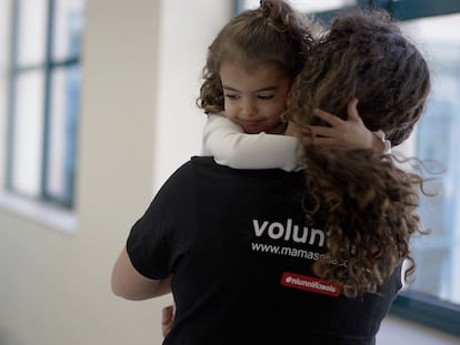 Una niña es acompañada por una voluntaria de Mamás en Acción.