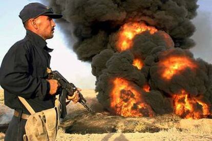 Un policía iraquí hace guardia junto a un oleoducto en llamas, después de un ataque insurgente, ayer en Kirkuk (Irak).