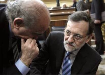 El presidente del Gobierno, Mariano Rajoy (d) y el ministro de Interior, Jorge Fernández Díaz, conversan durante la segunda sesión del debate del estado de la nación que tiene lugar hoy en el Congreso de los Diputados.