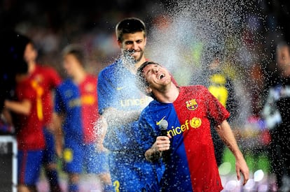 Pique riega con cava a su compañero Messi al término de un partido de Liga entre el Barcelona y el Osasuna, para festejar el doblete de campeones de la Copa del Rey y de la Liga, en 2009.