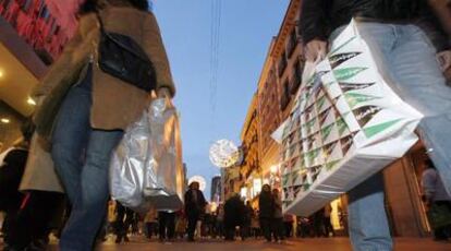 Ciudadanos cargados con bolsas de regalos, en la céntrica calle de Preciados, en el último fin de semana de compras antes de la Navidad.
