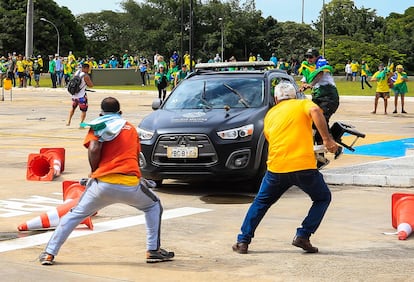 Partidarios del expresidente brasileño Jair Bolsonaro atacan un vehículo de la Policía Militar durante los enfrentamientos frente al Palacio Presidencial.