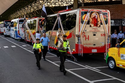 Agentes de la Policía cargan una imagen de la Virgen del Carmen que adornará uno de los vehículos del desfile, en la terminal de transporte del norte de Medellín, el 16 de julio de 2025.