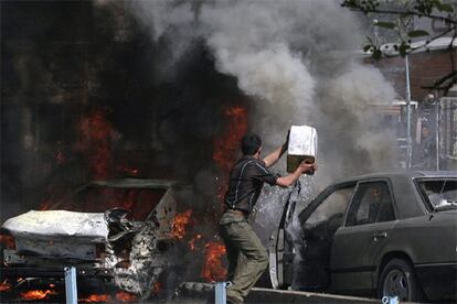 Un iraquí trata de apagar el fuego después de uno de los coches bomba que ha explotado en Bagdad y que ha causado la muerte de 10 personas.