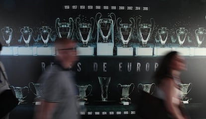 Dos visitantes pasan frente a un mural con el palmarés del Real Madrid.