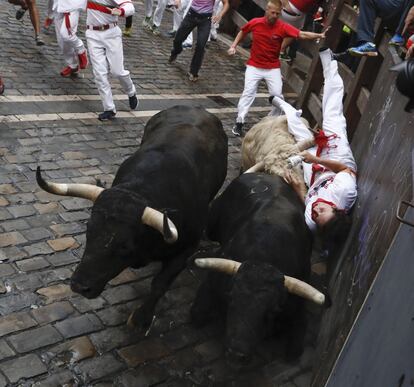 Los toros de la ganadería de Jandilla atrapan a un mozo contra la barrera en la curva de Mercaderes.