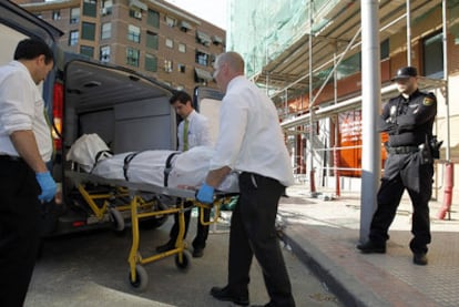 El cuerpo de uno de los dos obreros fallecidos es introducido en un furgón funerario.