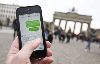Una persona utiliza su móvil frente a la Puerta de Brandenburgo, en Berlín
