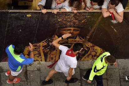 Algunos corredores junto a la imagen de San Fermín momentos antes del séptimo encierro.