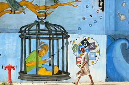 Un hombre pasa frente a un mural, en Colombo (Sri Lanka). El Gobierno del país ha anunciado que comenzará a imponer multas y penas de cárcel a cualquier persona que ignore la normativa de seguridad sanitaria destinada a combatir la propagación del coronavirus.