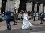 A newly-married bride walks past a terrace bar in the Plaza mayor in Madrid, Spain, Saturday, April 17, 2021. Spanish Prime Minister Pedro Sanchez says he is "very hopeful" that Spain can come up with its own COVID-19 vaccine by the end of the year. (AP Photo/Paul White)