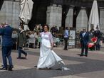 A newly-married bride walks past a terrace bar in the Plaza mayor in Madrid, Spain, Saturday, April 17, 2021. Spanish Prime Minister Pedro Sanchez says he is "very hopeful" that Spain can come up with its own COVID-19 vaccine by the end of the year. (AP Photo/Paul White)