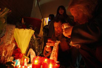 Dos mujeres ponen velas en la ceremonia de la estación del Pozo.