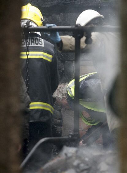 Varios forenses y bomberos buscan el cuerpo de uno de los desaparecidos en el incendio en Aranga (A Coruña).