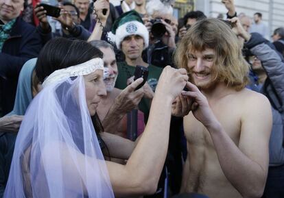 Gypsy Taub, coloca un anillo en el dedo de Jaymz Smith, durante su boda nudista frente al ayuntamiento de San Francisco. Taub, es el rostro visible del movimiento por los derechos nudistas de San Francisco, se casaron frente al ayuntamiento y más tarde fue detenido y liberada por la policía.