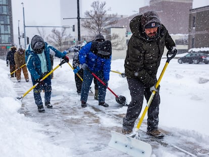 Trabajadores retiran nieve de las banquetas en Des Moines, Iowa, el 12 de enero 2024.