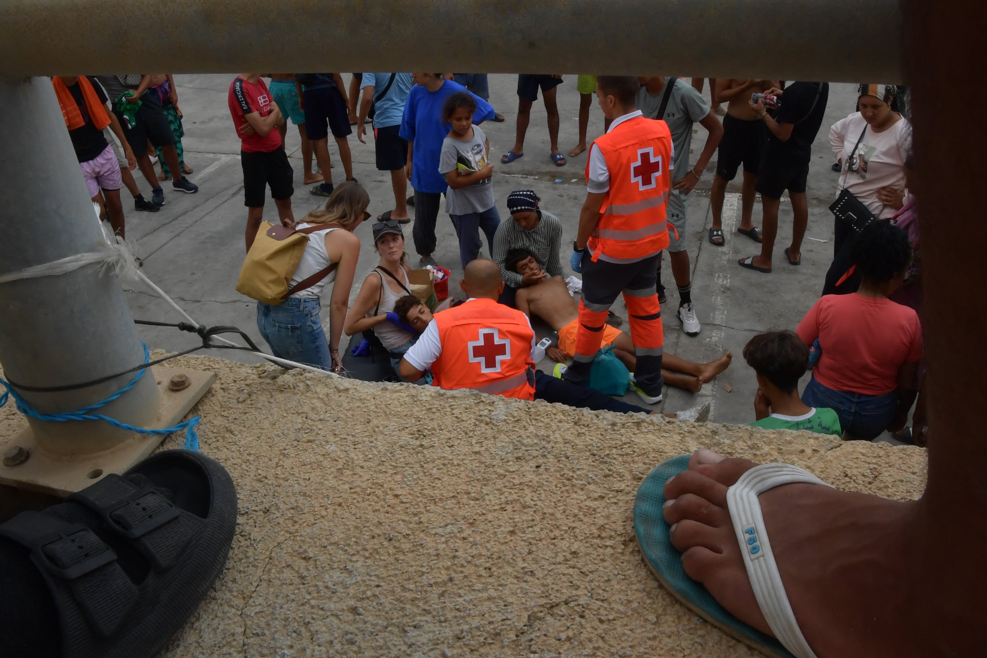Dos migrantes desplomados en el suelo por la falta de comida y agua son atendidos por sanitarios.
