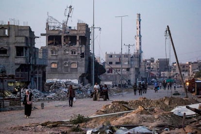 Varios gazatíes caminan entre edificios bombardeados en Jan Yunis.