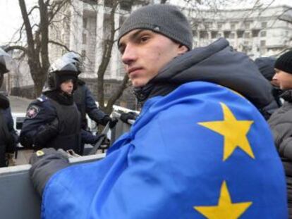 Un manifestante con una bandera europea frente a una barrera policial en Kiev.
