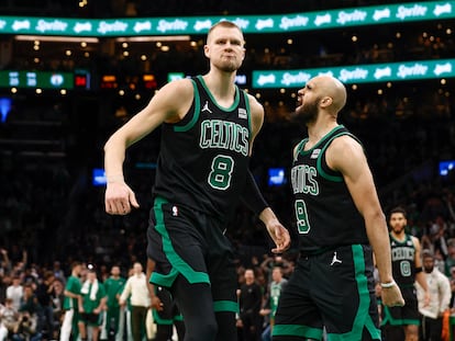 El escolta de los Boston Celtics Derrick White (a la derecha) celebra un mate del pívot Kristaps Porziņģis en un partido contra los Milwaukee Bucks