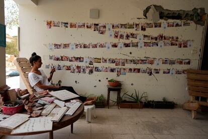 Una mujer se sienta junto a una pared dañada donde cuelgan retratos de víctimas, mientras Israel conmemora el primer aniversario del ataque de Hamas contra Israel, en el Kibutz Beeri, este lunes.