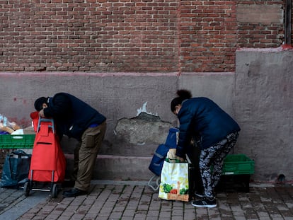 Personas recogiendo la comida que les han entregado en la parroquia de San Ramon Nonato de Madrid, en febrero de 2021.