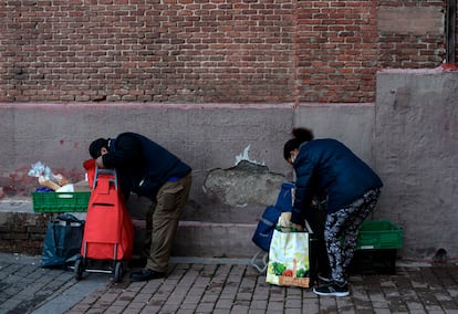 Personas recogiendo la comida que les han entregado en la parroquia de San Ramon Nonato de Madrid, en febrero de 2021.