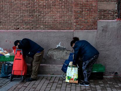 Personas recogiendo la comida que les han entregado en la parroquia de San Ramon Nonato de Madrid, en febrero de 2021.