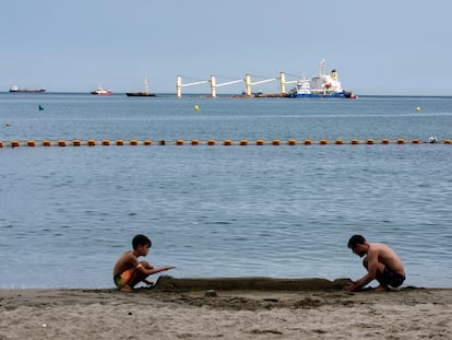 Un niño y un hombre juegan en una playa de Gibraltar este pasado jueves, tras el vertido provocado por el accidente del granelero 'OS35'.